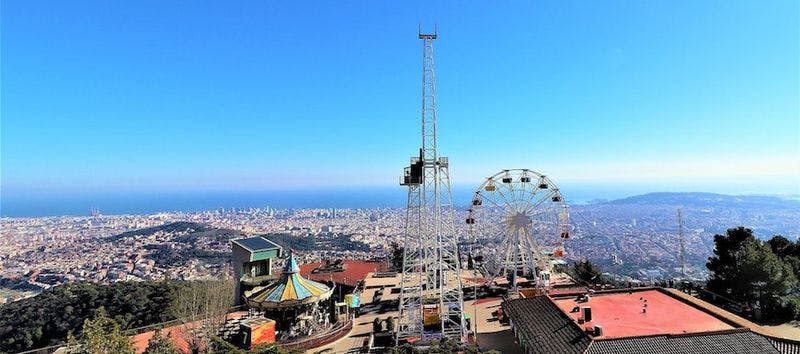 Amusement park rides atop a hill looking down at a view from Tibidabo