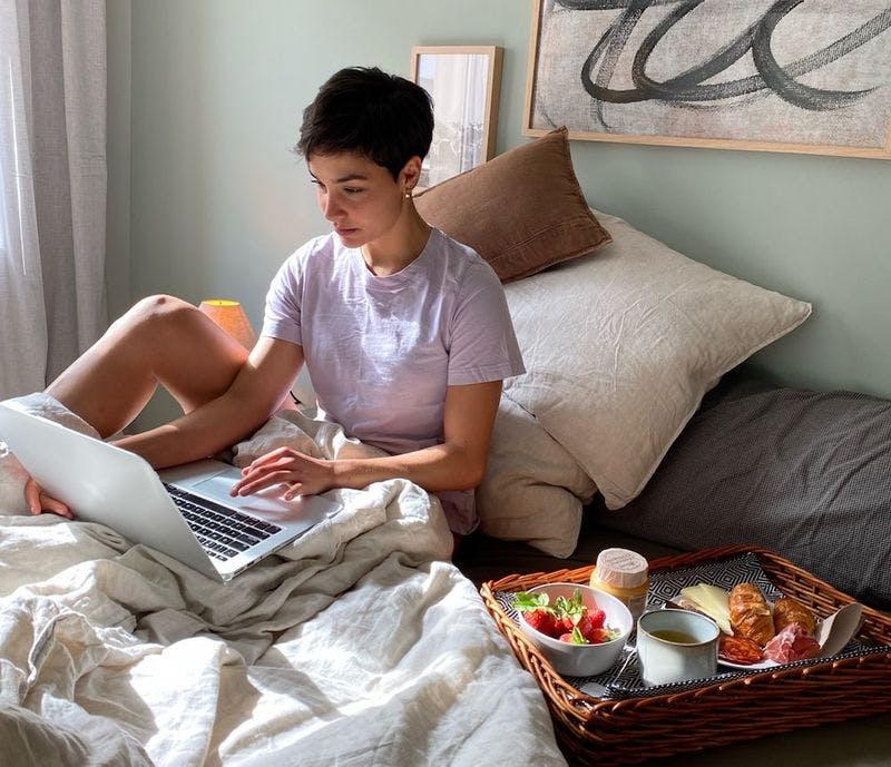 woman in bed with food working on computer