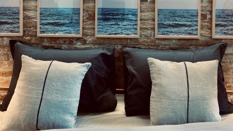 blue and white pillows with brick wall with ocean photos