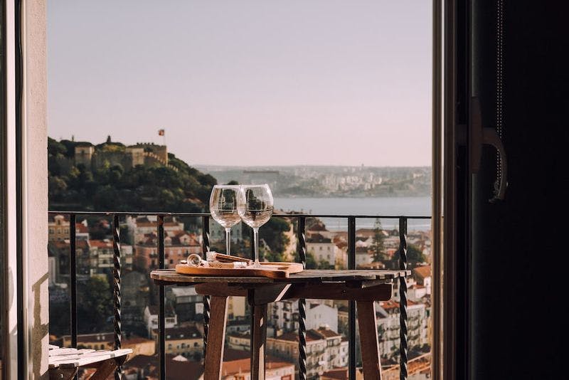 two glasses of wine on a balcony with a view of lisbon